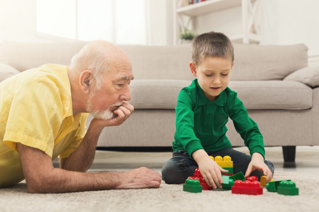 Boy playing with grandfather in building kit